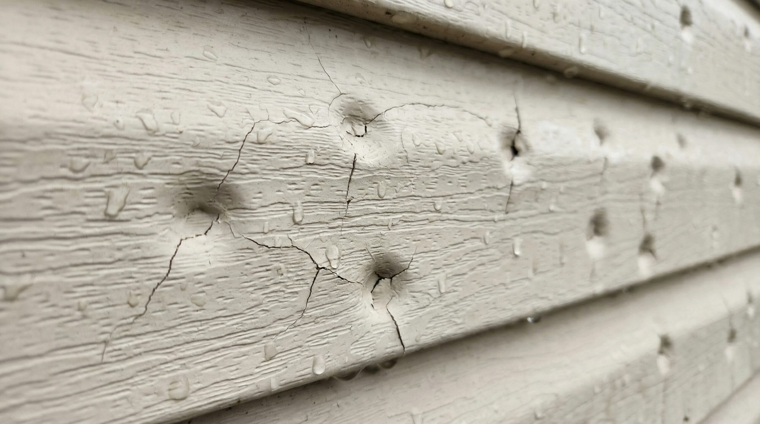 Close-up of hail damage on vinyl siding
