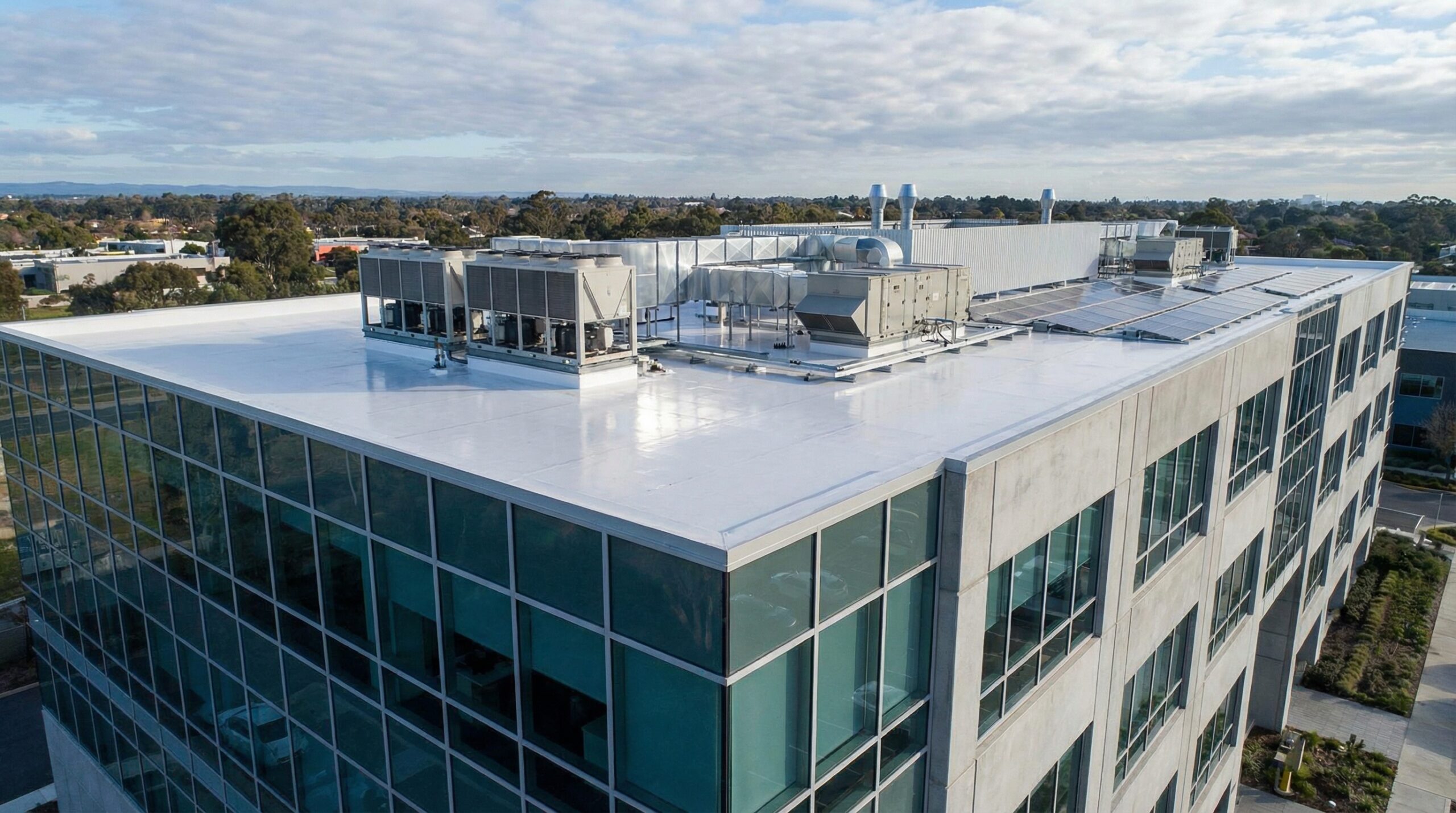 Commercial building with white TPO roof showing HVAC equipment and proper drainage systems