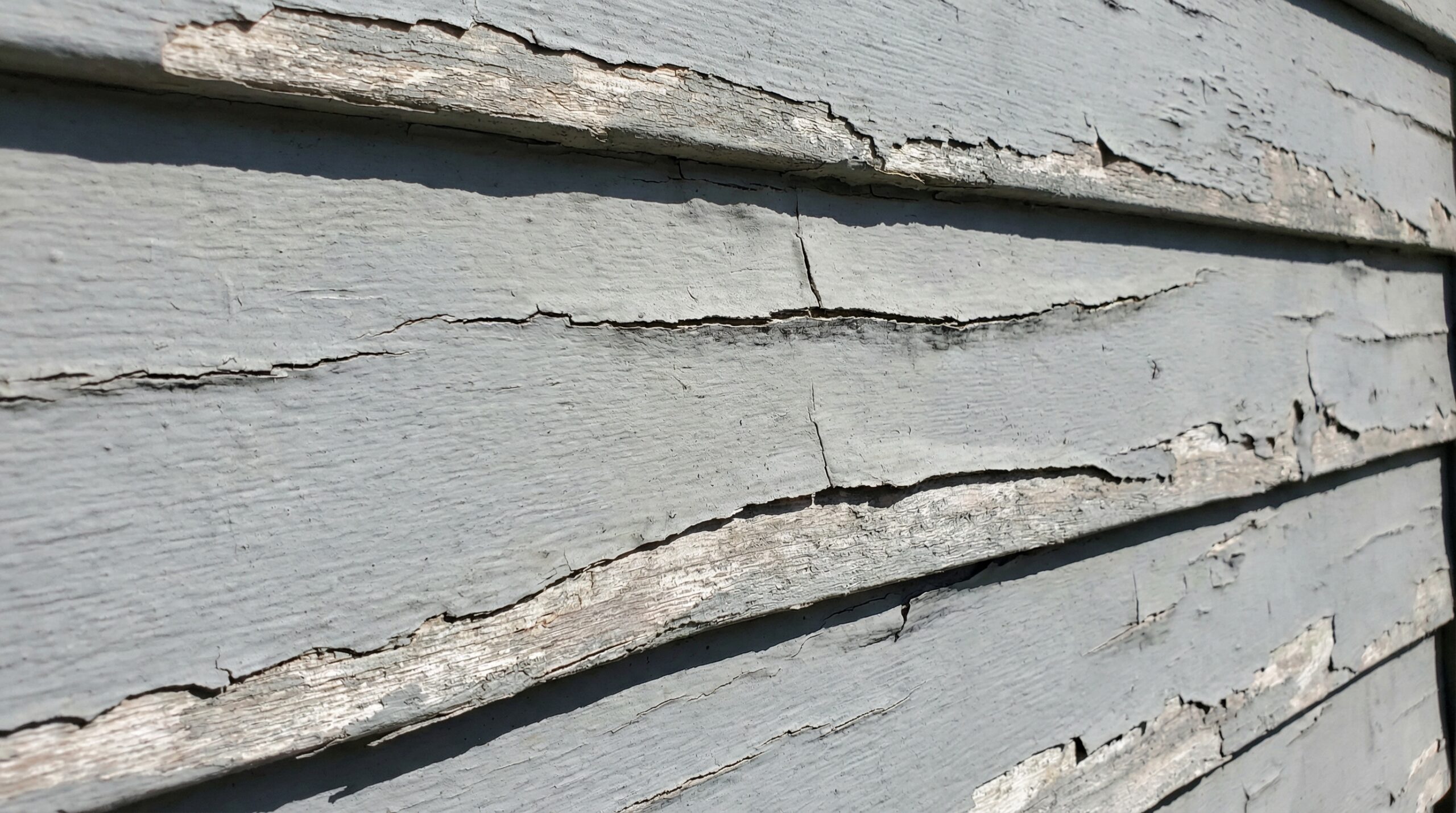 Damaged vinyl siding showing cracks and warping on Northeast Ohio home