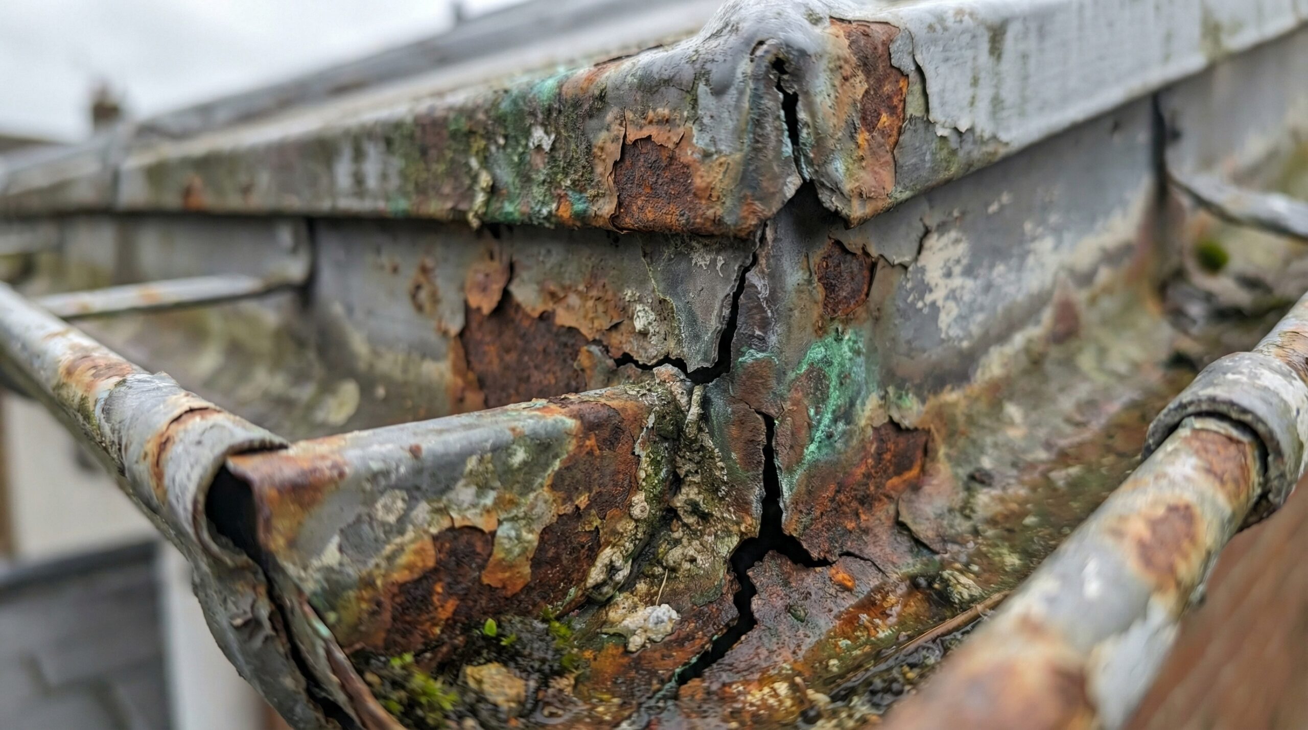 Close-up of gutter showing rust corrosion and cracks