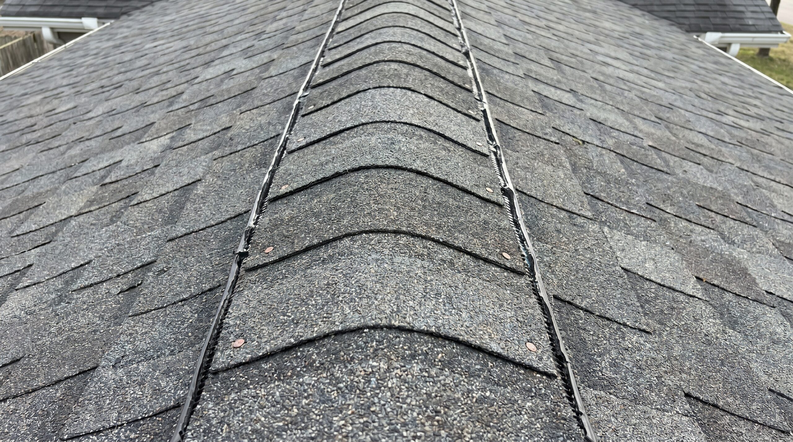 Close-up photo of properly installed ridge cap on asphalt shingle roof