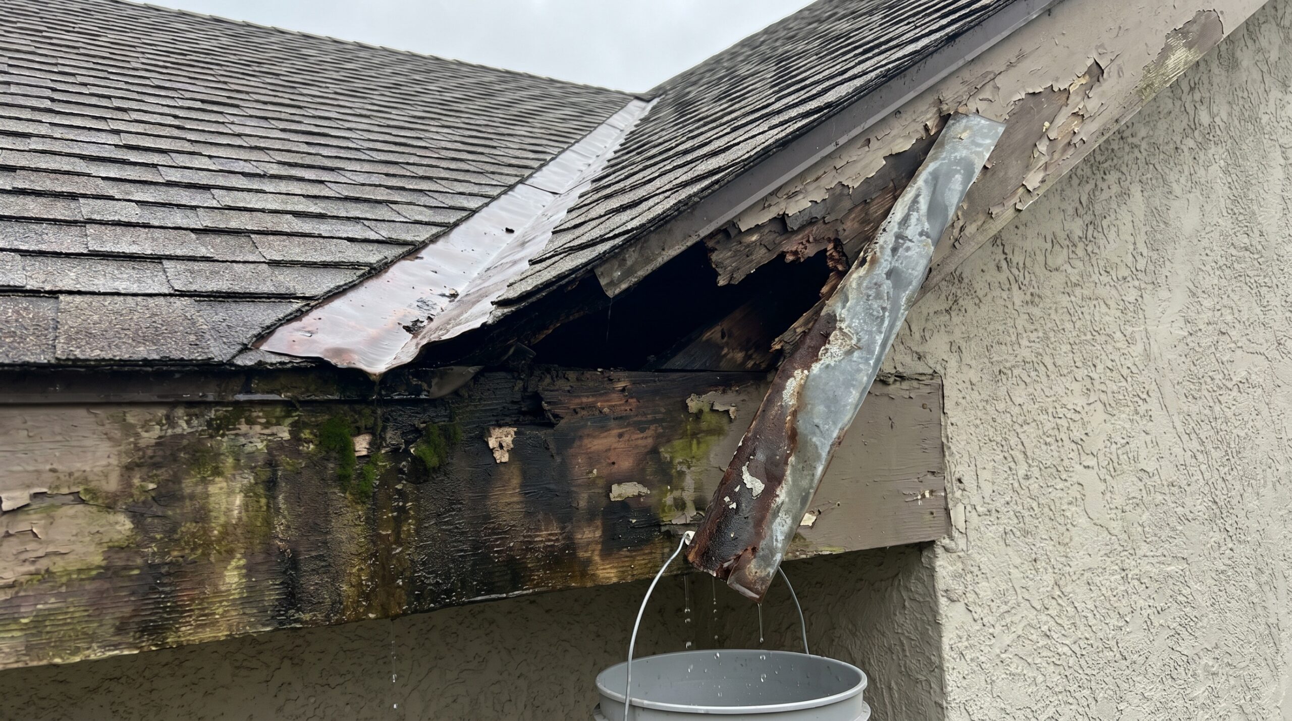 Photo showing water damage and rot at a roof-wall intersection with missing or failed flashing